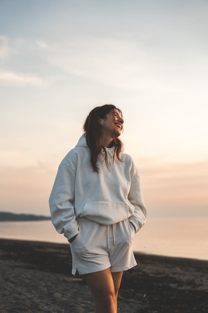 A woman in white sweatshirt and shorts standing on the beach